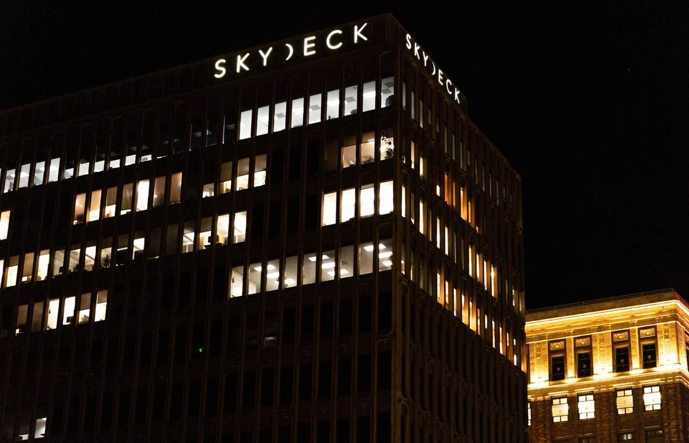 The SkyDeck sign lit at night on the corner of a high-rise building